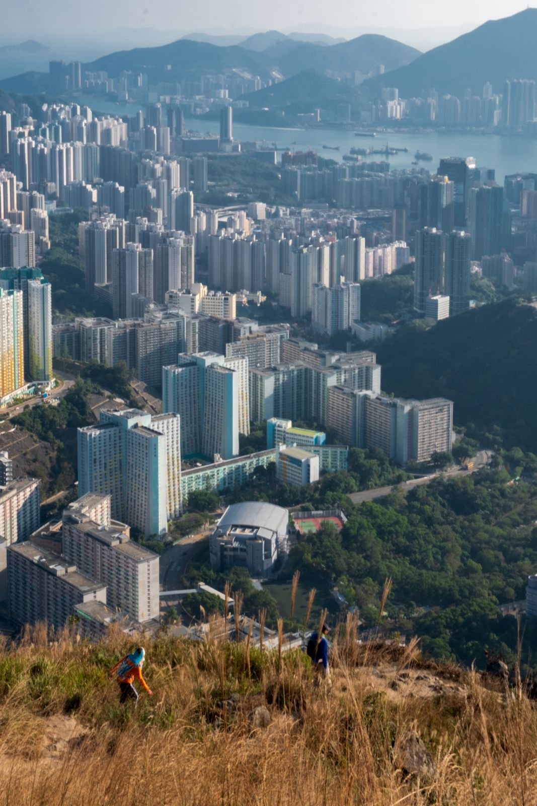 A couple of hikers cautiously descends from  from the Suicide Cliff on December 1, 2020 in Kowloon with Victoria Harbour and Hong Kong island in the distance.