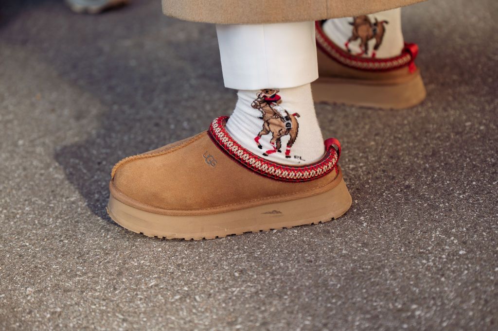 COPENHAGEN, DENMARK - FEBRUARY 02: A guest wearing a white top, white pants, beige coat, Dior bag, brown Ugg shoes, black sunglasses, and beige fluffy fur bucket hat outside Helmstedt during the Copenhagen Fashion Week Autumn/Winter 2023 on February 02, 2023 in Copenhagen, Denmark. (Photo by Raimonda Kulikauskiene/Getty Images)