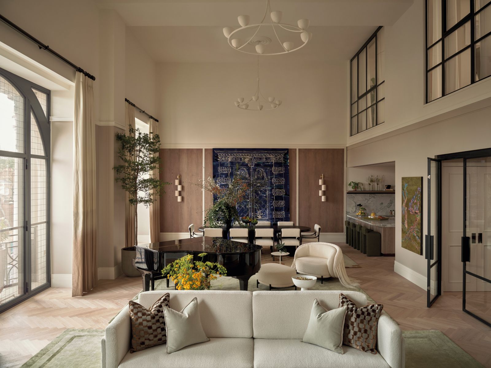 A grand piano mediates the living and dining areas while a wall-hung blue tapestry lends a vibrant touch