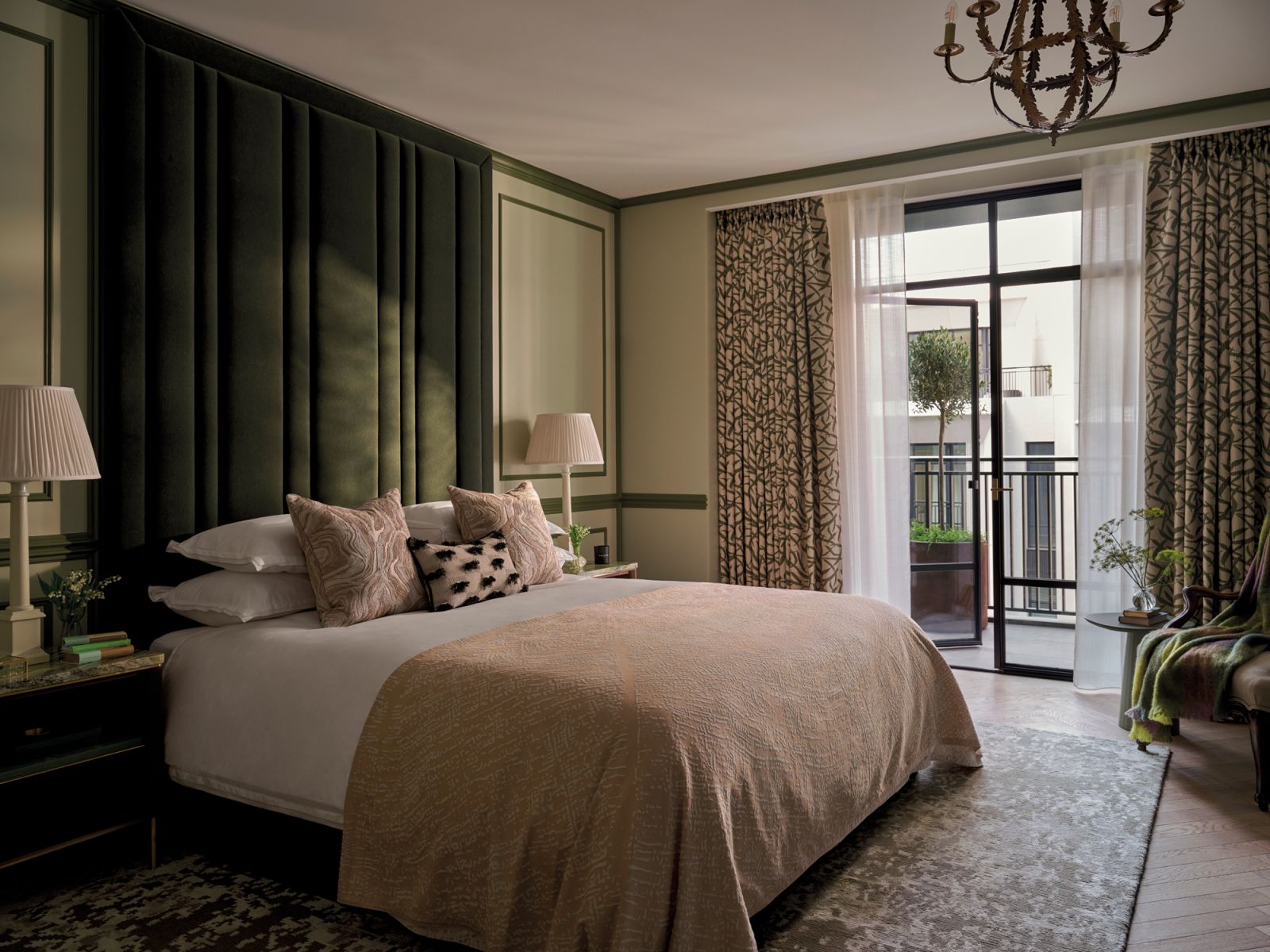 In another bedroom, a tall, deep-green headboard and foliage-motif curtains bring the outdoors in