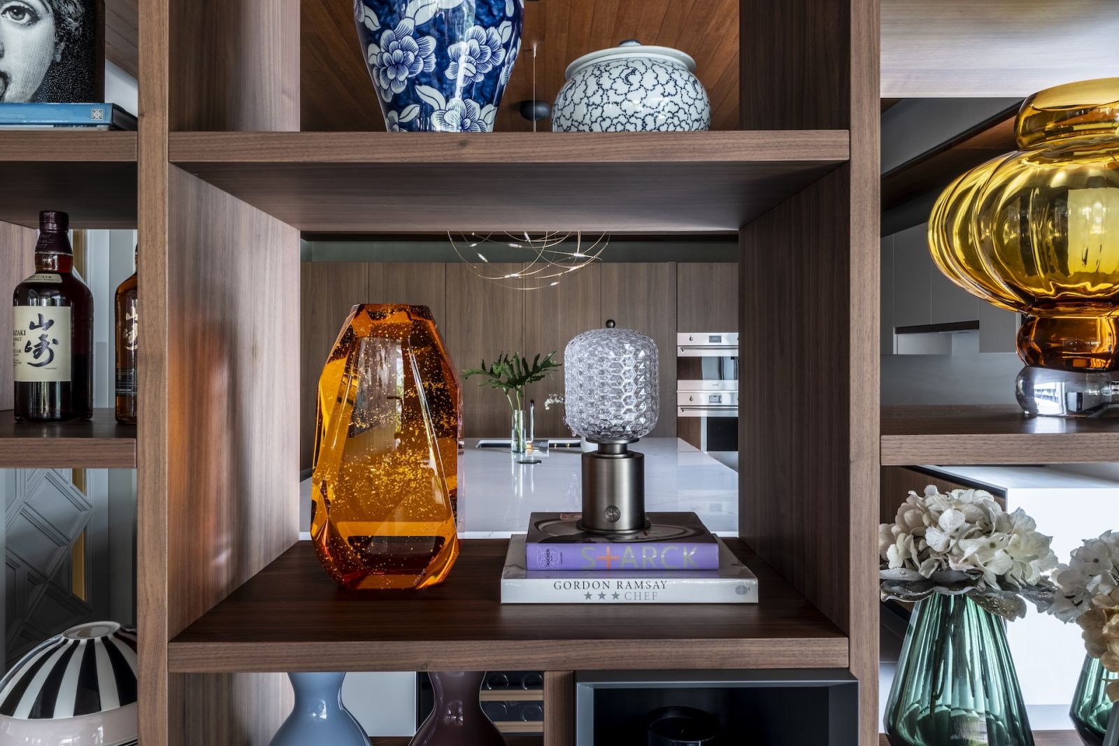 The shelf of vases, figurines and books that separates the dining area from the kitchen