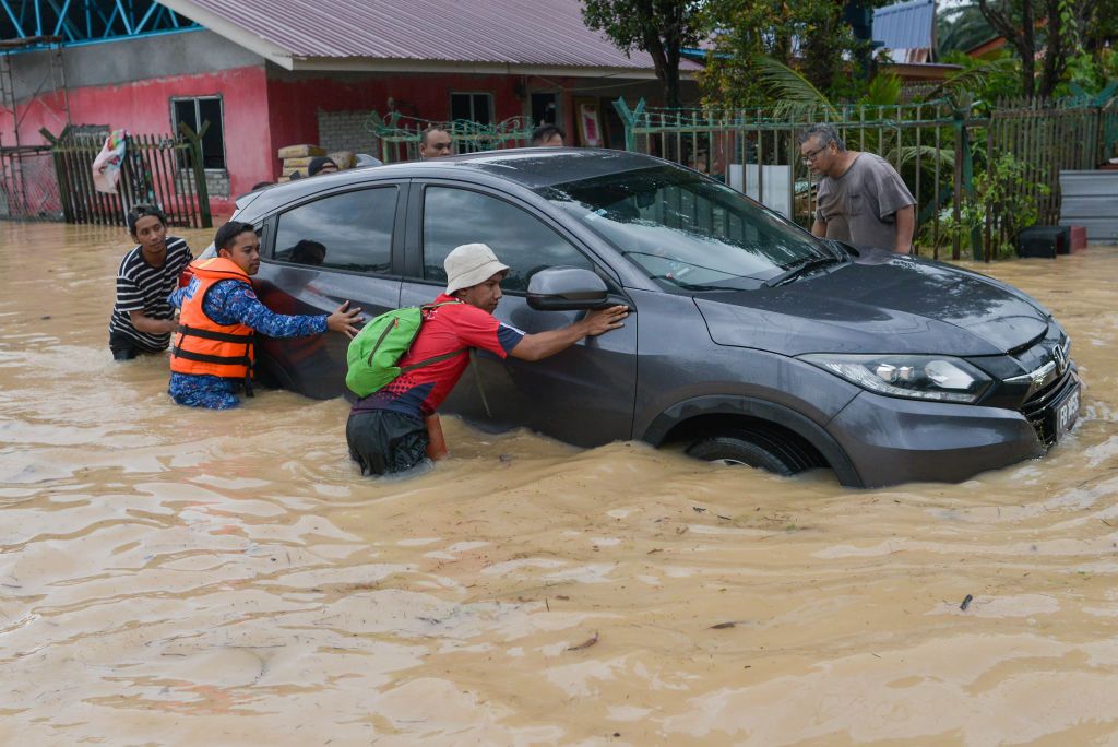 People rescue a car in a flooded street at their resident in Klang, Malaysia on November 10, 2022 (Photo by Zahim Mohd/NurPhoto via Getty Images)