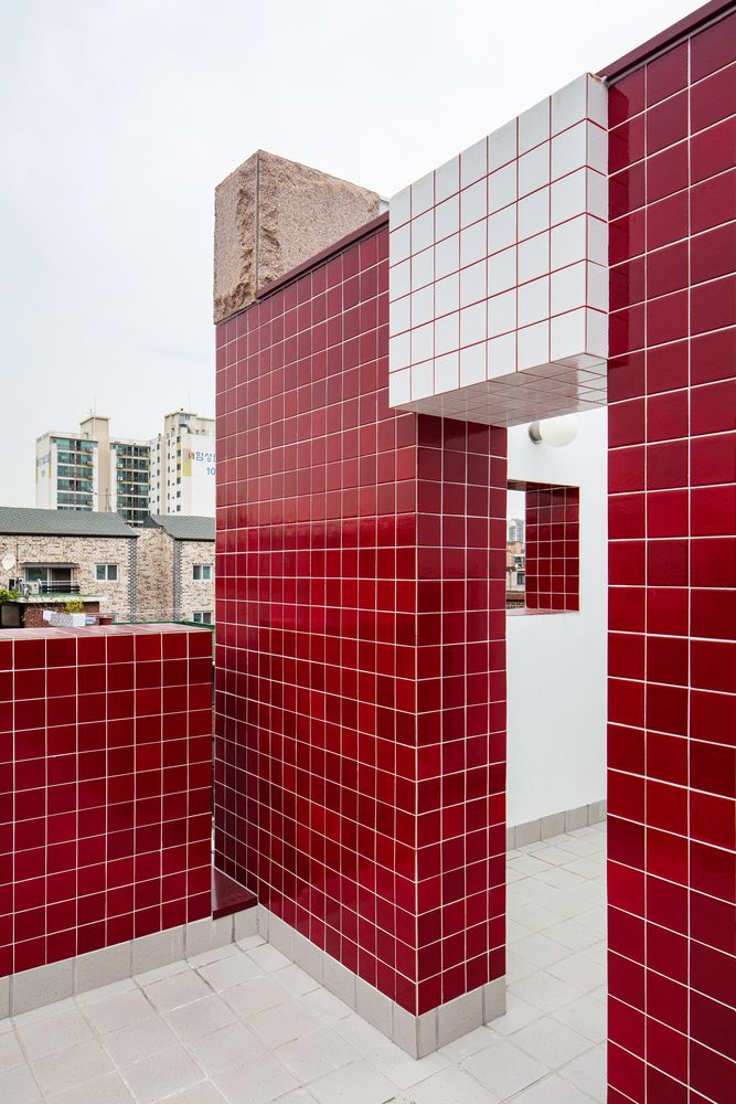 Glossy red tiles with white tile joints and accents of rough stone panels (Photo: Instagram / @klink_architecture)