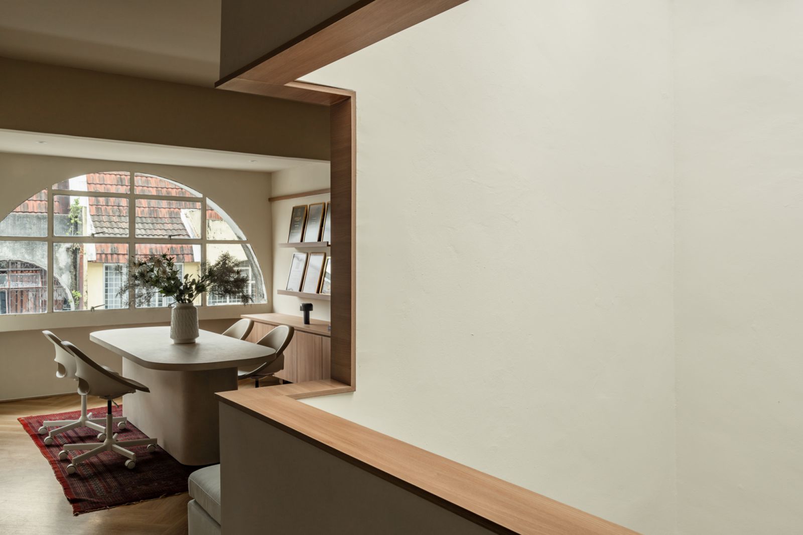A meeting area with an oval table set against arched windows overlooking neighbouring buildings