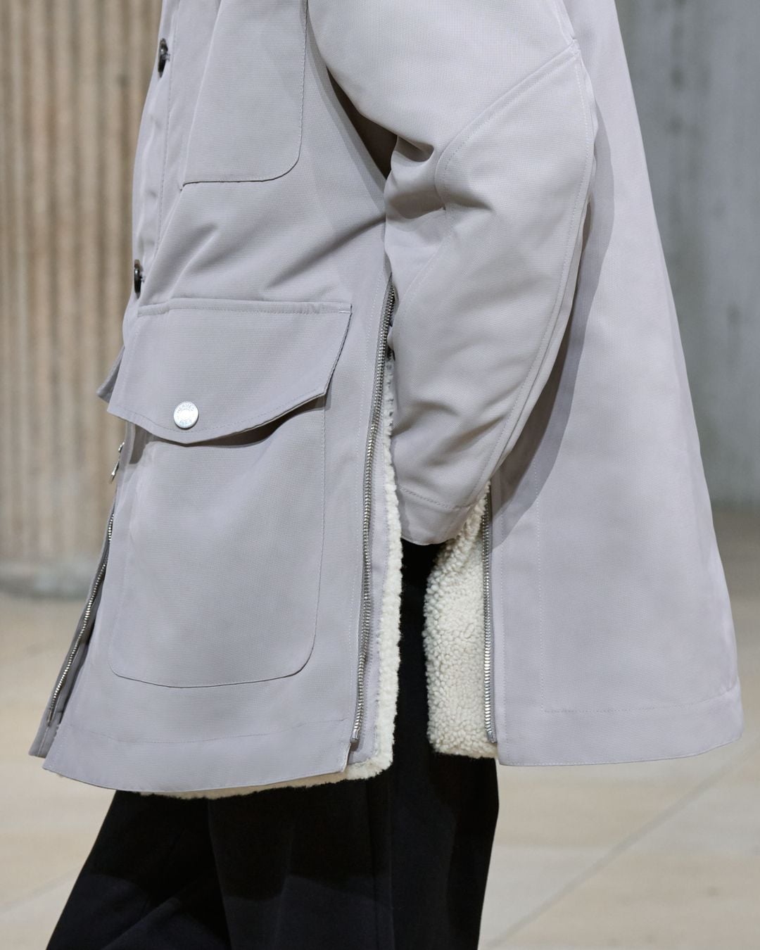Chiếc áo khoác parka xẻ tà được thiết kế để người mặc có thể đút tay vào túi quần. Kiểu thiết kế túi áo mang nắp vốn gây “thừa thãi” cho đôi bàn tay được Hermès cân bằng công thái hoàn hảo, giữ cho quý ông dáng vẻ tự tin, lịch lãm. Ảnh: Hermès