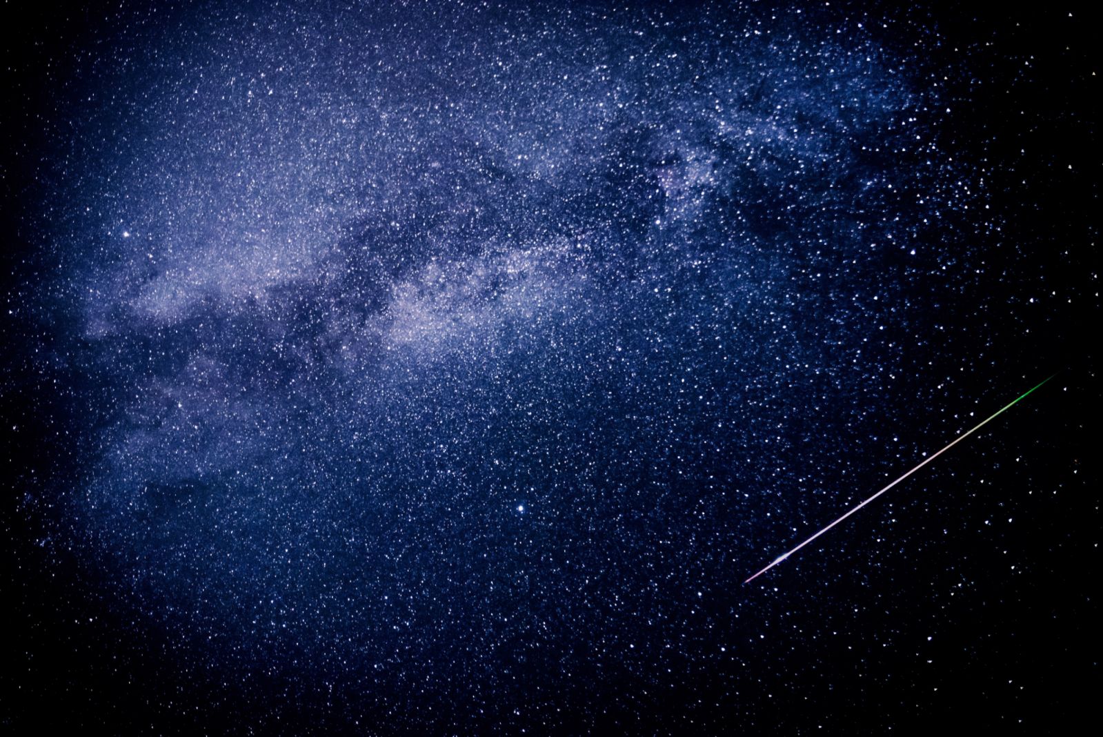 A meteor shoots across the night sky sky leaving a trail of light across the milky way
