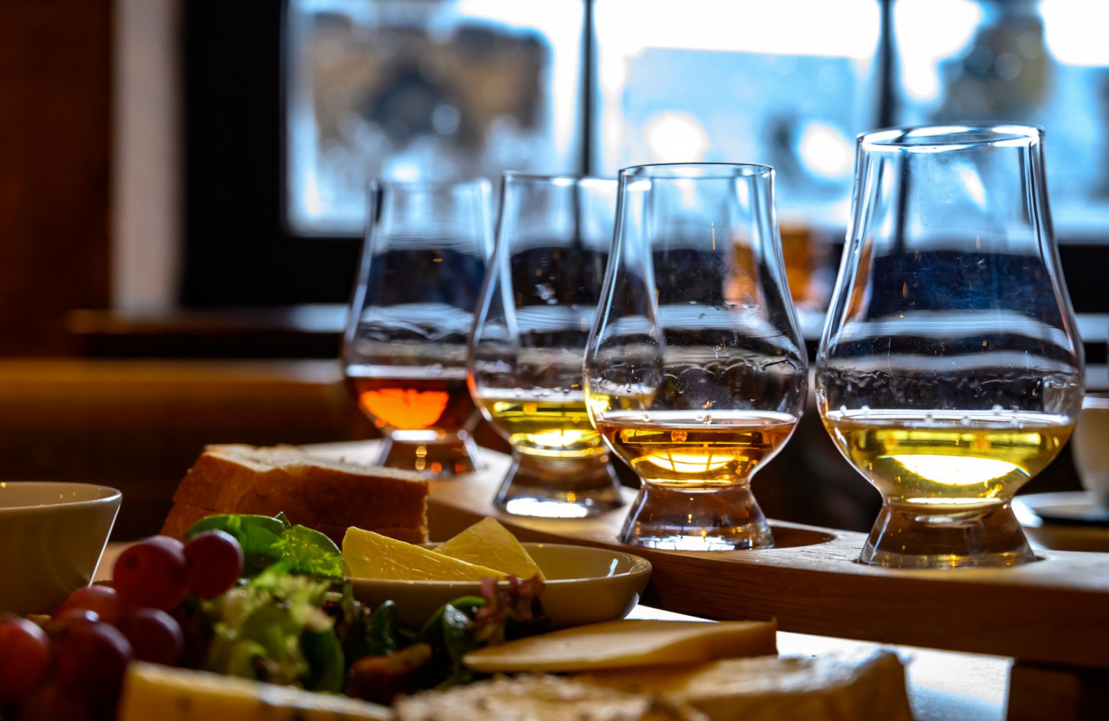 Tasting of original scottish cheese and whisky, plate with scottish cheeses and variety of Scotch in glasses in pub