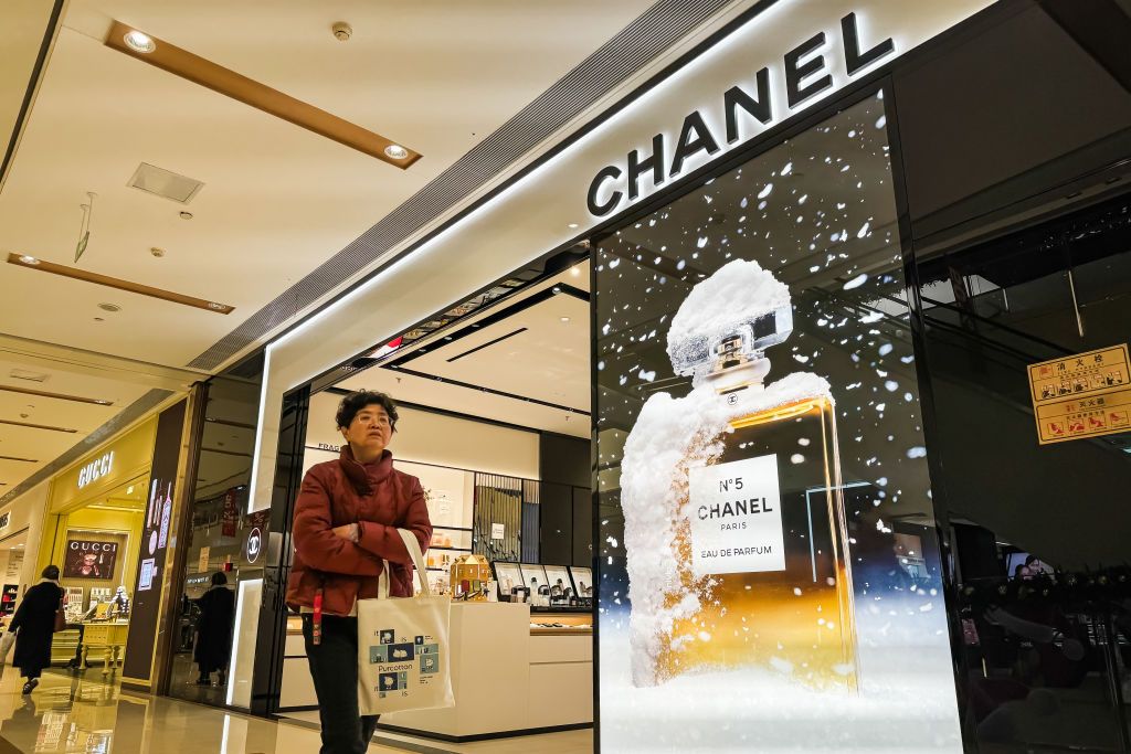 CHONGQING, CHINA - DECEMBER 17: A shopper carrying a bag walks past a Chanel store featuring a prominent display of Chanel No. 5 perfume inside a luxury shopping mall on December 17, 2024 in Chongqing, China. The demand for luxury brands such as Chanel continues to grow as Chinese consumers prioritize premium fragrances and cosmetics. (Photo by Cheng Xin/Getty Images)