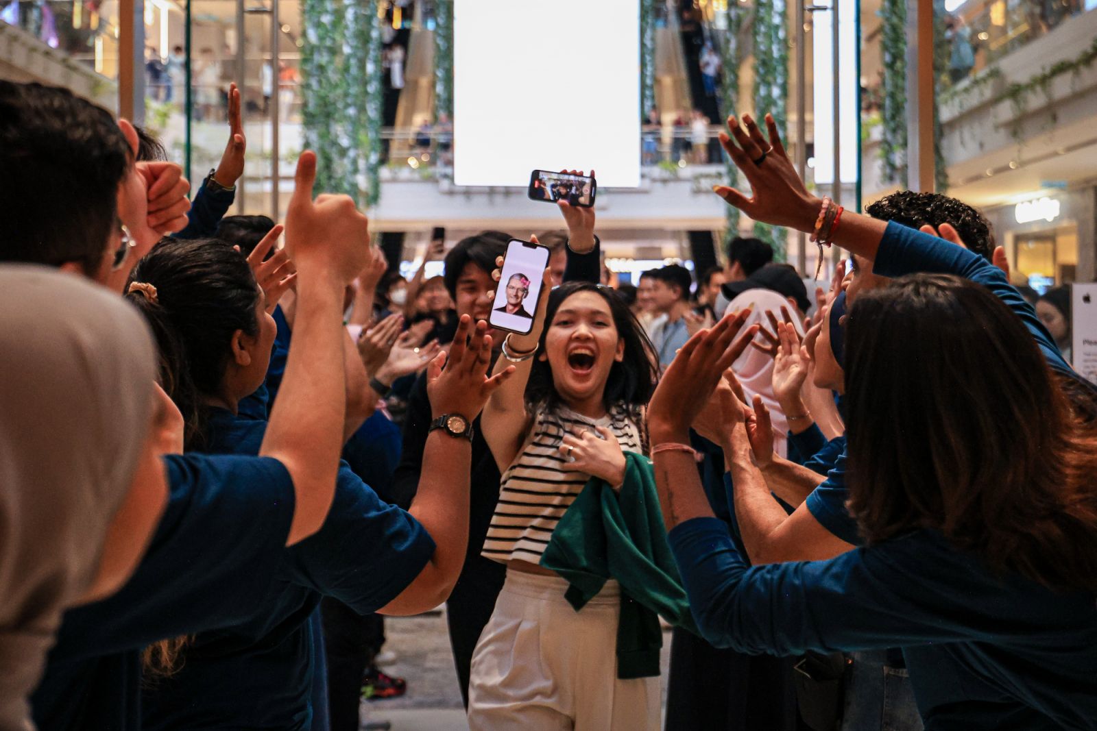 KUALA LUMPUR, MALAYSIA - JUNE 22: A customer walks into the new Apple store holding a picture of Tim Cook as she is welcomed by the store staff at the Tun Razak Exchange (TRX) on June 22, 2024, in Kuala Lumpur, Malaysia. Apple’s first retail location in Malaysia’s capital, Kuala Lumpur, officially opens at the Exchange TRX, offering a full lineup of products and services, support from over 160 team members, and sessions with local creatives. This marks its sixth store in Southeast Asia and further expands i