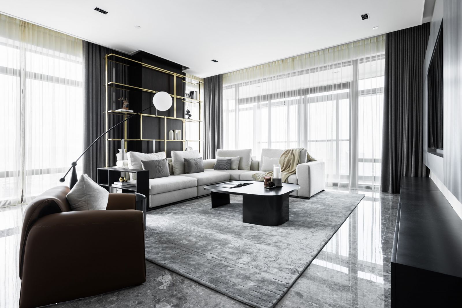 The open-plan living space features a plush sectional sofa and sculptural floor lamp