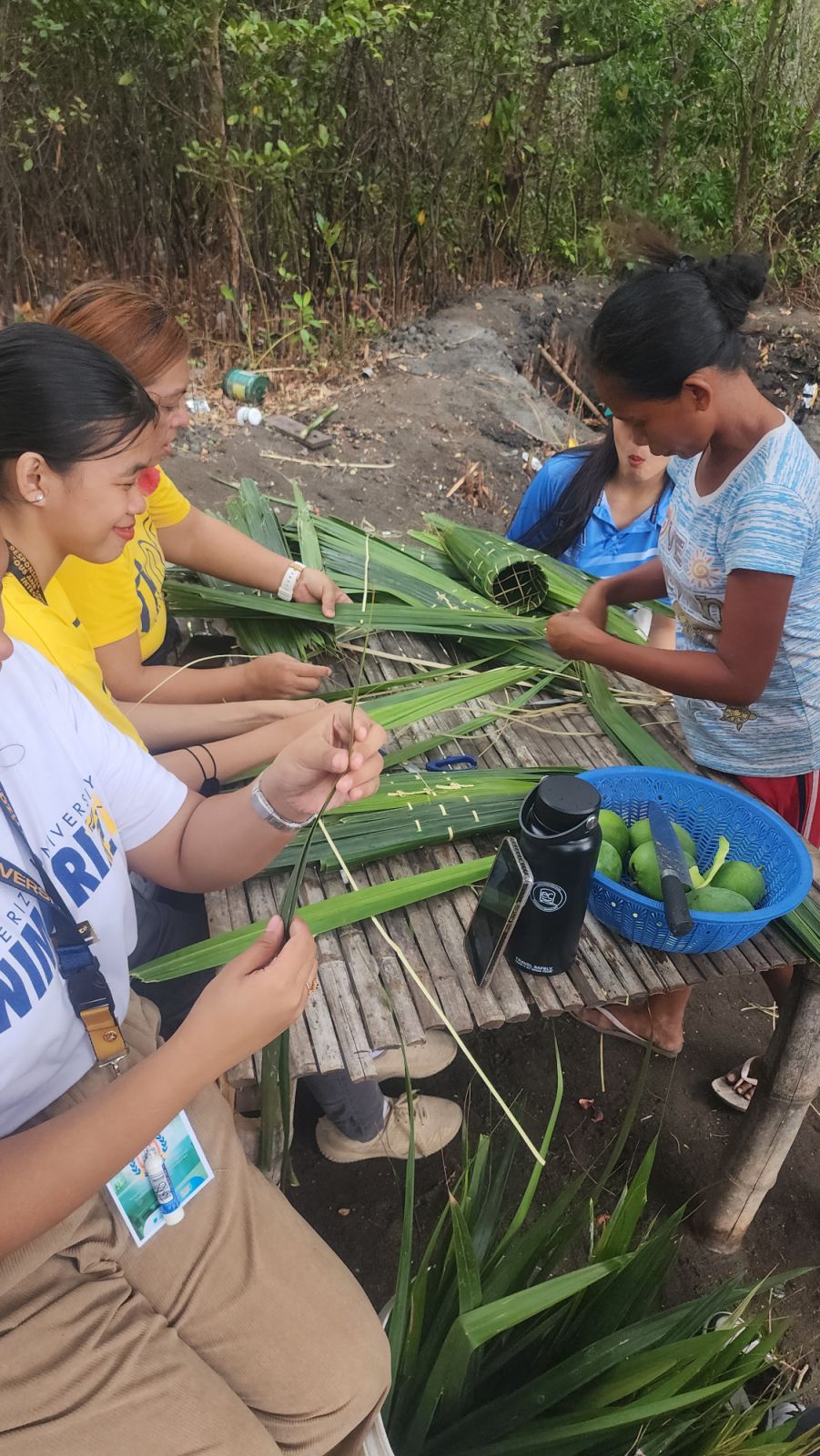 Students working with Filipina farmers in wrapping the salt in buy-o, a cylindrical, biodegradable basket made of woven bamboo and rattan