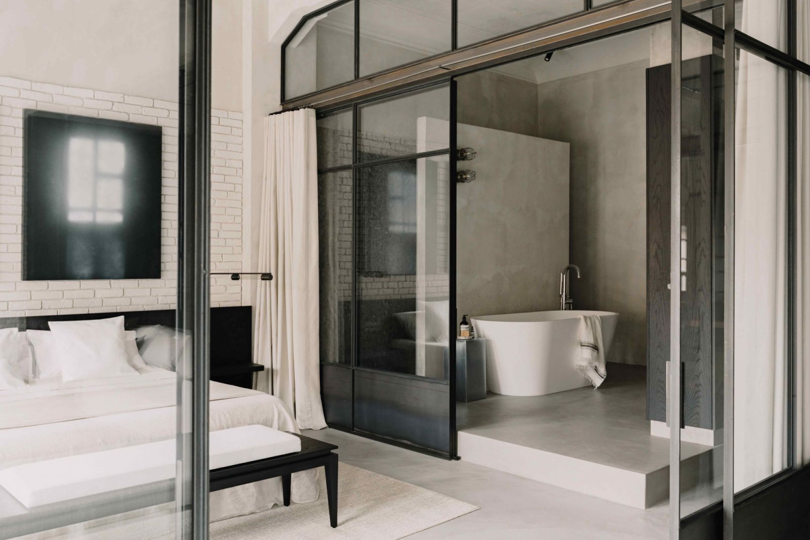 The adjoining main bathroom separated by a glazed partition and curtains