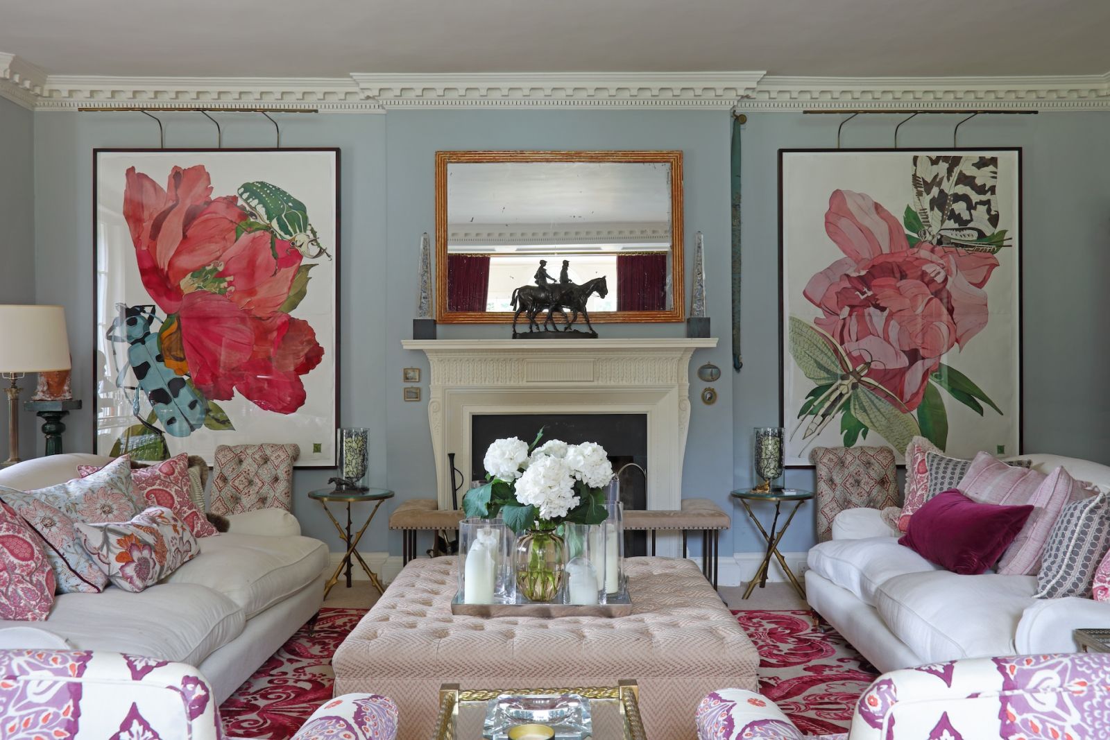 A vivid drawing room in Annoushka Ducas' Sussex, England home, with artworks by Sarah Graham, a rug by The Rug Company, a restored antique marble fireplace and intricate decorative cornices