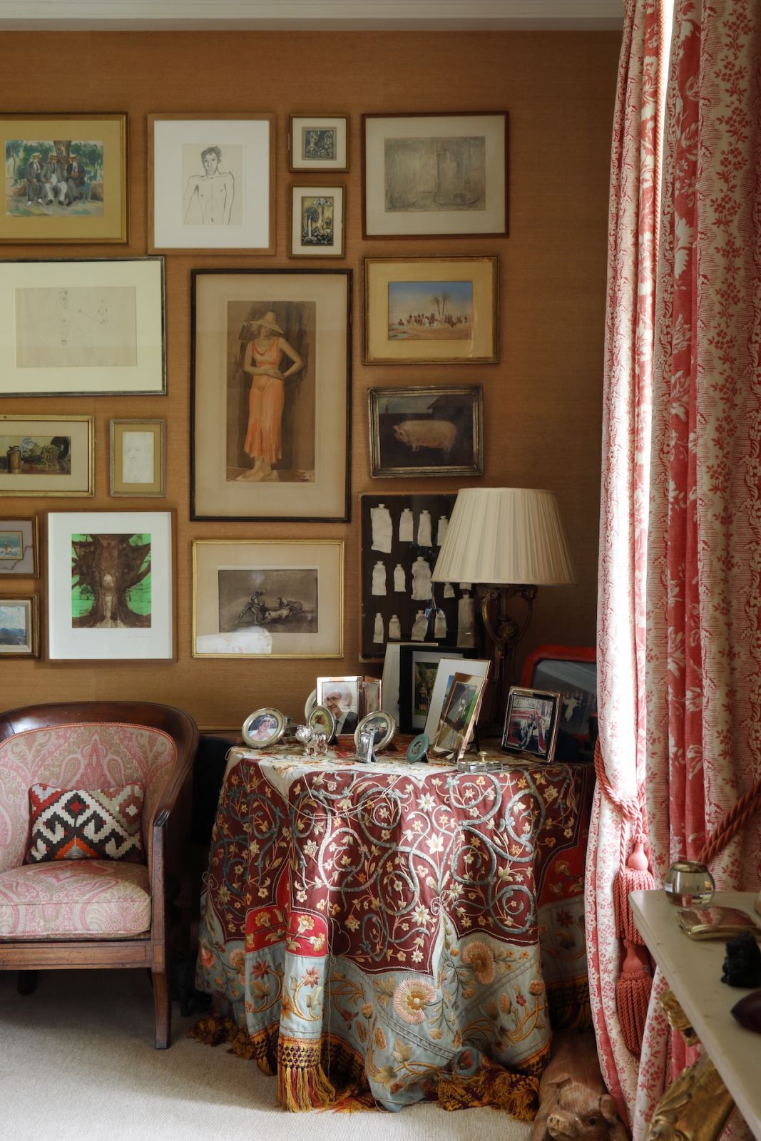 An accent wall, covered in warm ochre hessian, features a curation of family artworks and photographs in this Sussex, England home