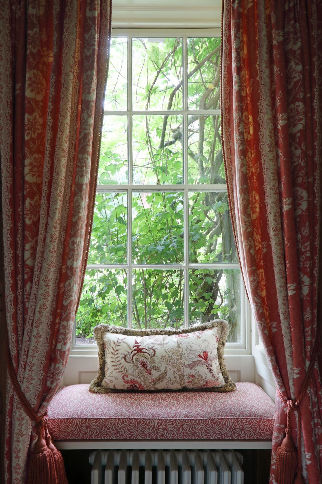 The window seats in this snug family room conceal radiators, and their cushions feature Fermoi fabric, complemented by Justin Van Breda cushions and curtains by Colefax and Fowler