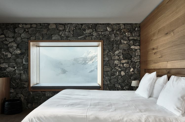 Rough stone elements juxtapose oak panels and plush bedding (Photo: Design Hotels)