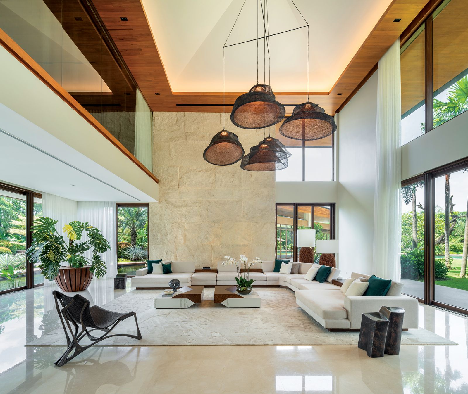 The second living room features Miguel Aguas ceiling lamps, OMO Furniture corner lamps and an accent wall of Monumental Travertine from Kaufman Stone