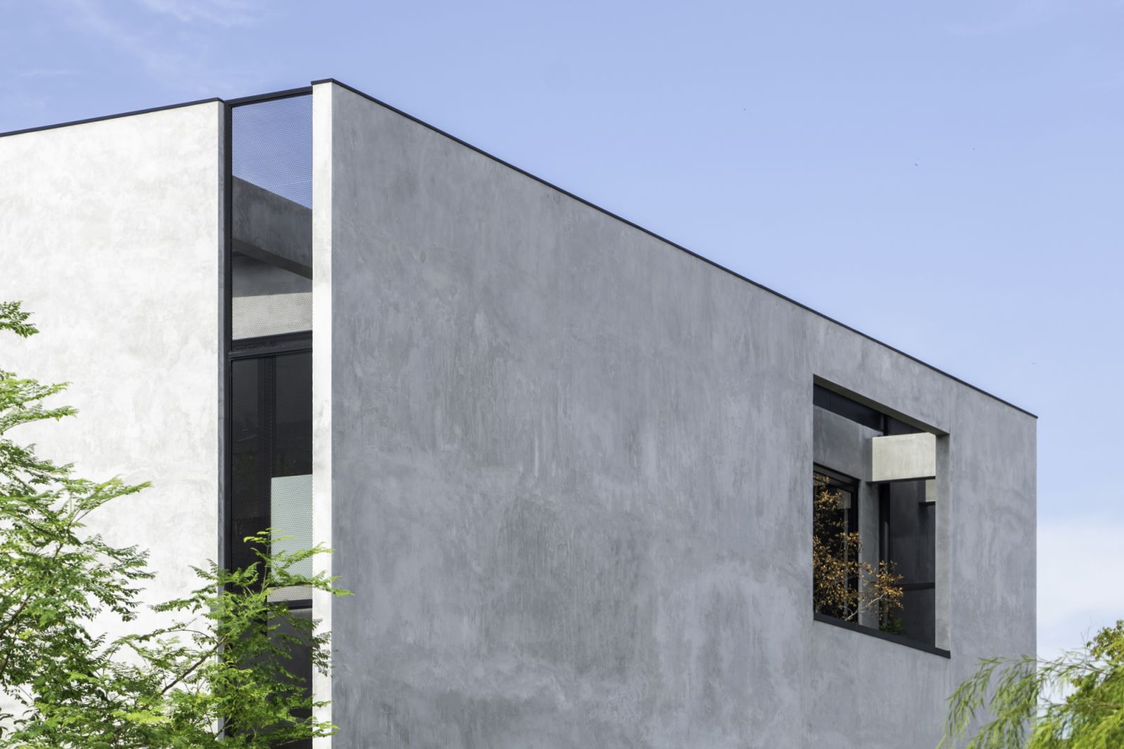 A close-up view of the minimalist exterior, featuring clean lines and a modern cement skim finish on the walls