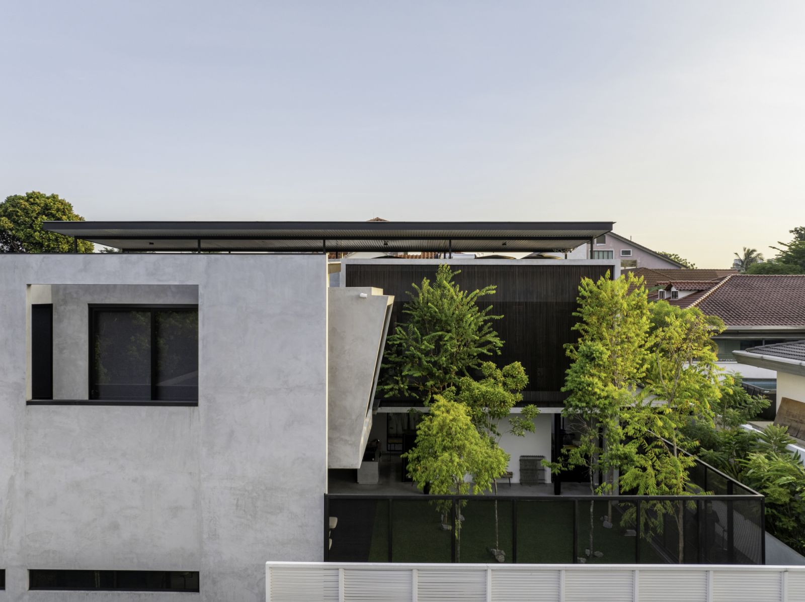 A side view of the home showing the relationship between the solid concrete volumes and the lush courtyard spaces.