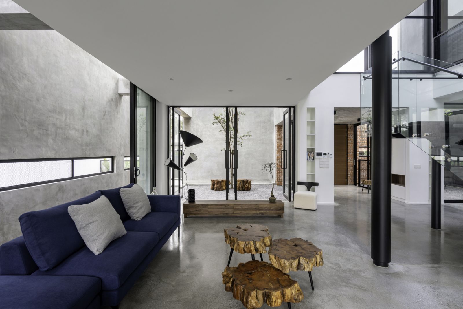 A deep navy sectional sofa anchors the living area, complemented by a rustic wood slice coffee table that adds organic texture
