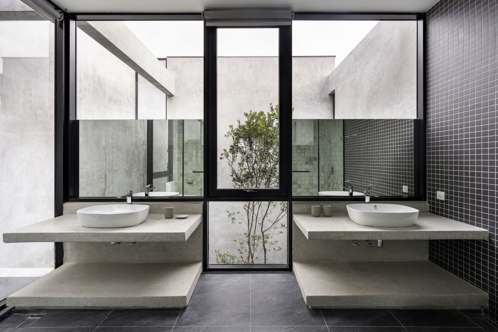 The double vanity bathroom showcases a symmetrical design with twin concrete countertops and vessel sinks