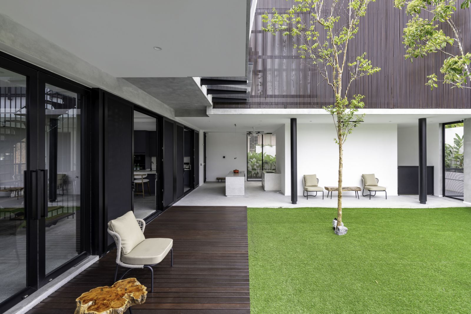 A dark Chengal wood deck extends from the interior, creating a transitional space between the living areas and the manicured lawn
