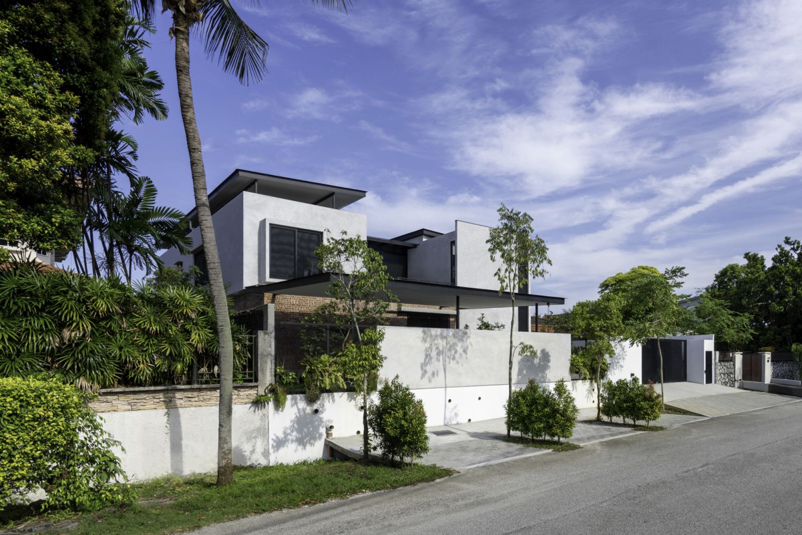 A street-level view of the Interlace House showing its distinctive modern facade against the tropical landscape