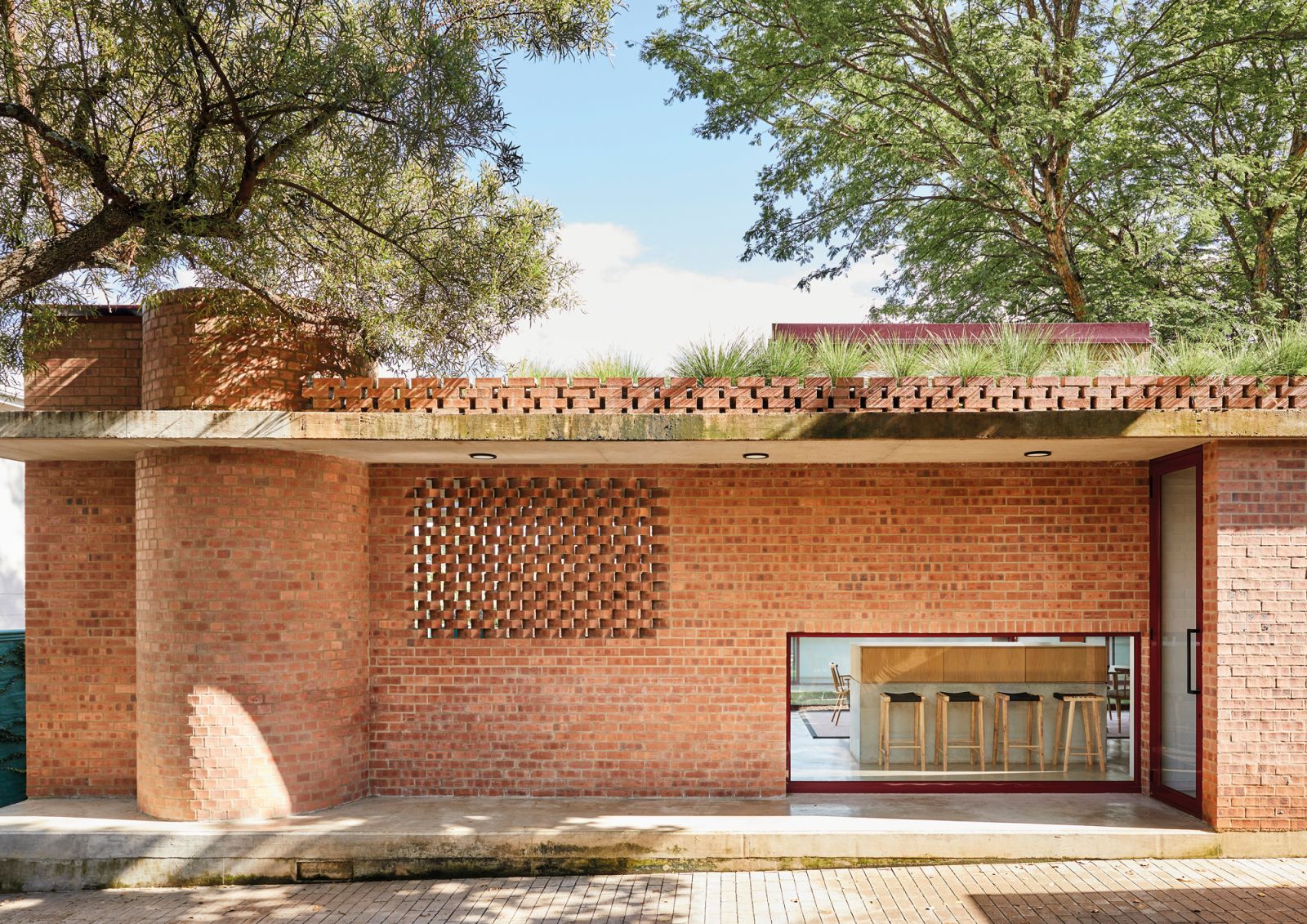 The straight-lined, low-slung character of the house and the expressive face-brick patterns—the cylindrical section houses a pizza oven