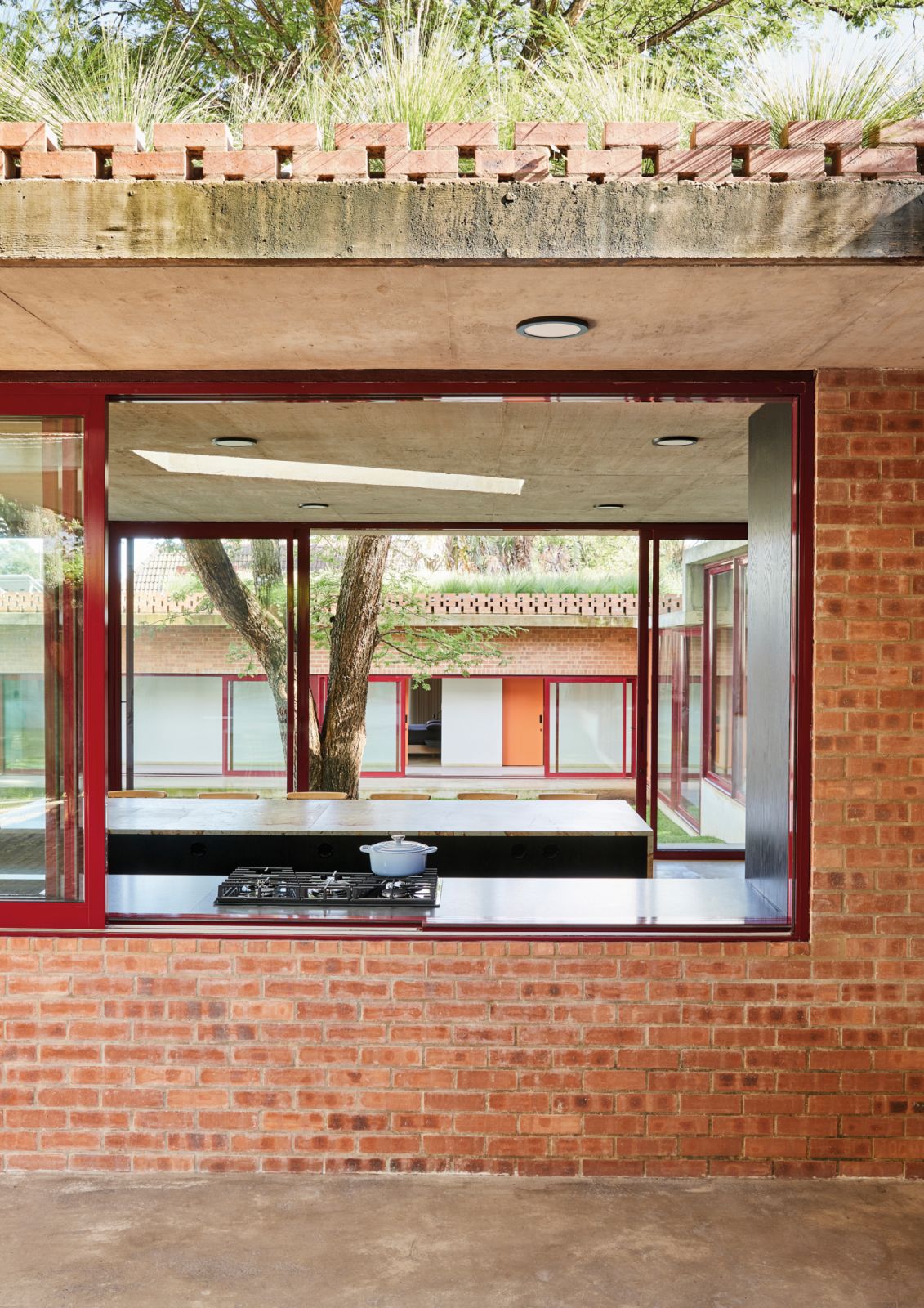 A large window above the kitchen counter opens a portal that draws the eye all the way through the living area and the courtyard beyond