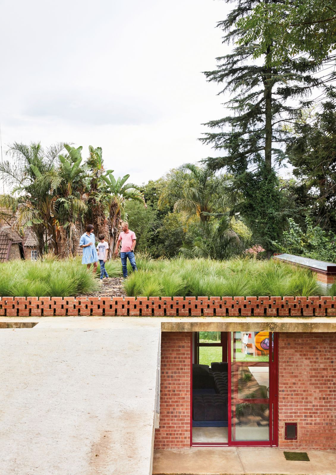 The wavy grass covering the rooftops makes it appear as if the ground has been ‘lifted’ above the footprint of the house, lending an almost subterranean quality to the interiors and blending beautifully with the surrounding trees