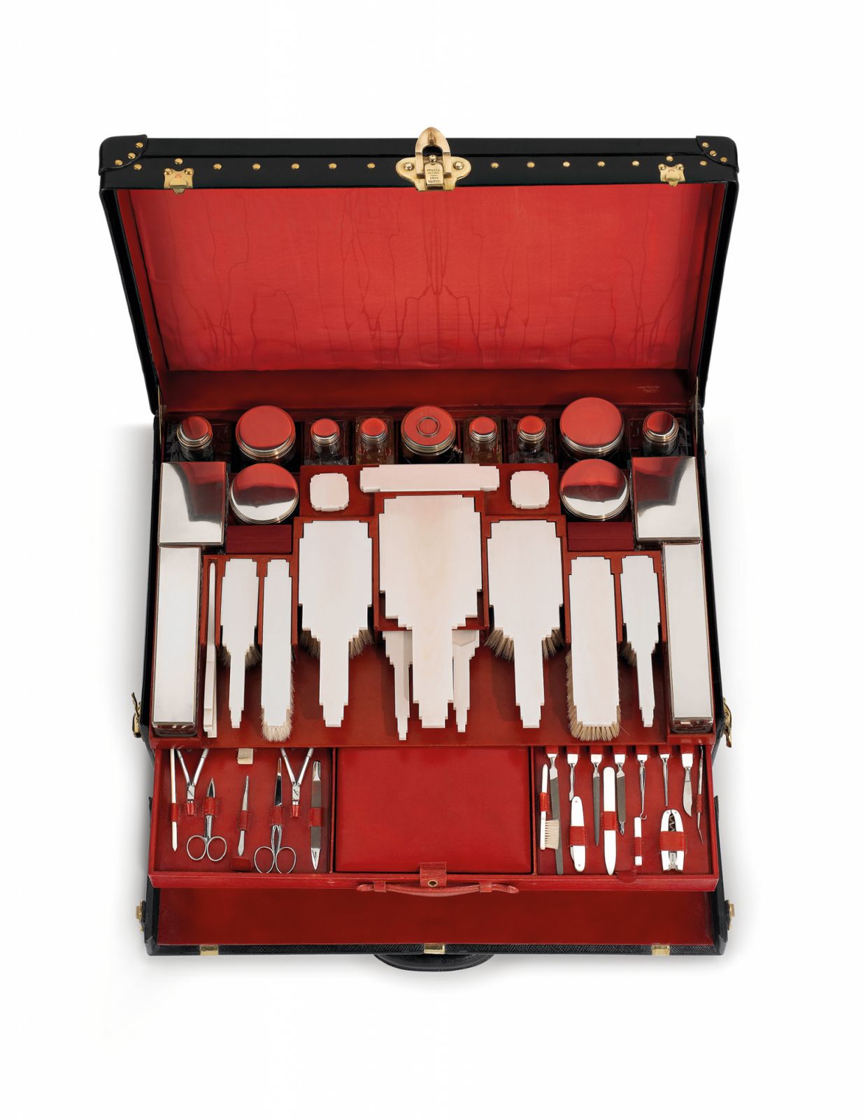 Porte-habits garni Milano en maroquin, 1925. Present au catalogue de la maison depuis 1914, ce porte-habits garni evolue au fil des styles et en fonction des demandes des clients. Gaine de maroquin noir, double de maroquin et de soie rouge, ce modele est une creation specifique a l'Exposition internationale des Arts decoratifs et industriels modernes de 1925. Sa garniture en ivoire, cristal taille et vermeil compte plus de cinquante pieces distribuees sur trois plateaux amovibles, parmi lesquelles necessair