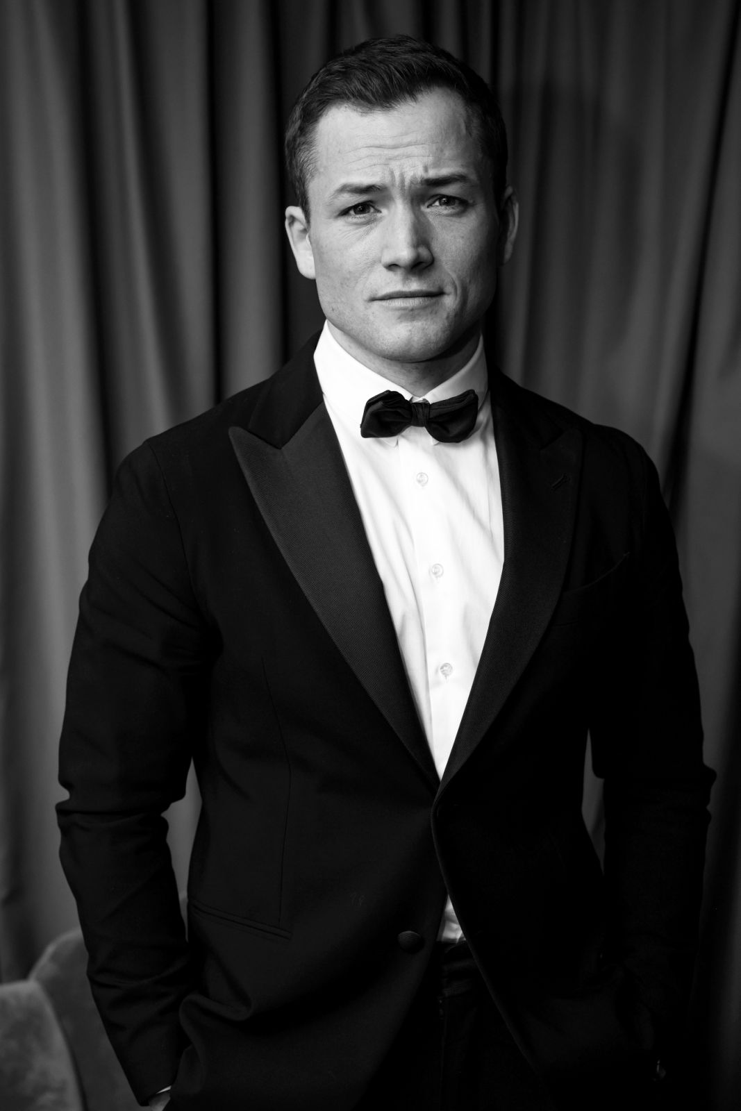 LONDON, ENGLAND - FEBRUARY 19: (EDITORS NOTE: This image has been converted to black and white.) Taron Egerton backstage during the EE BAFTA Film Awards 2023 at The Royal Festival Hall on February 19, 2023 in London, England. (Photo by Carlo Paloni/BAFTA via Getty Images)