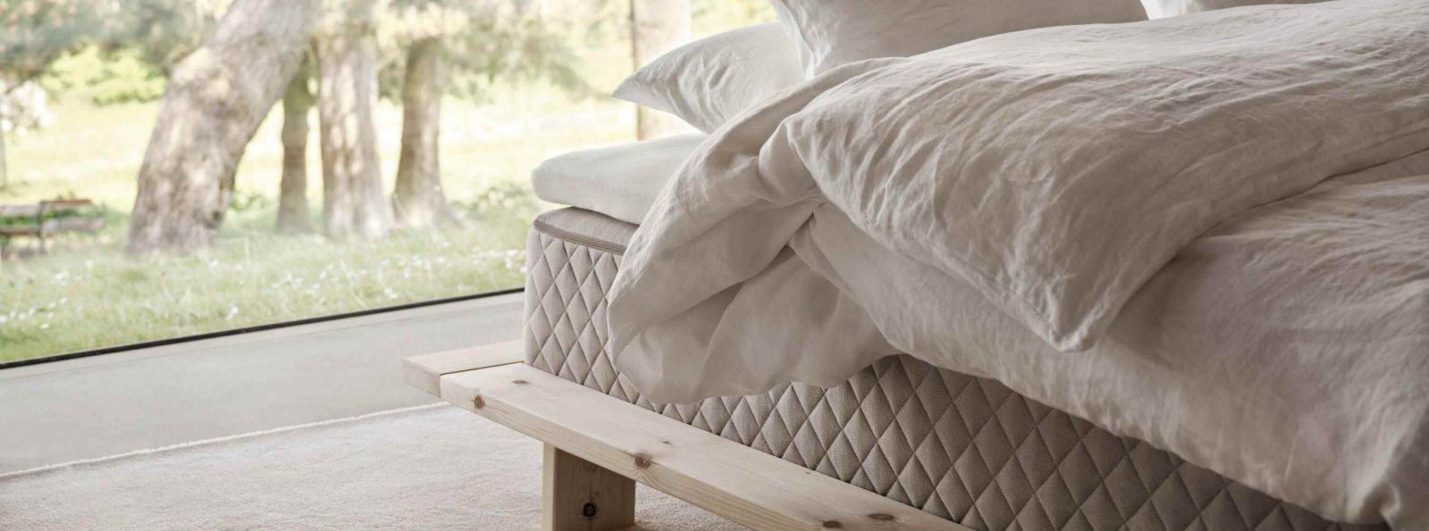 A close-up detail of a Duxiana mattress reveals its precision-quilted side panels and platform design