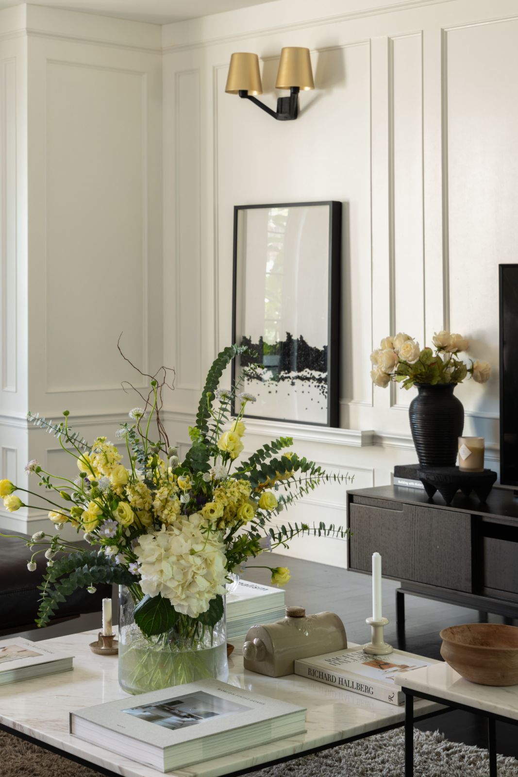A thoughtfully arranged corner of the living room showcases the intersection of white wood panelling and black flooring