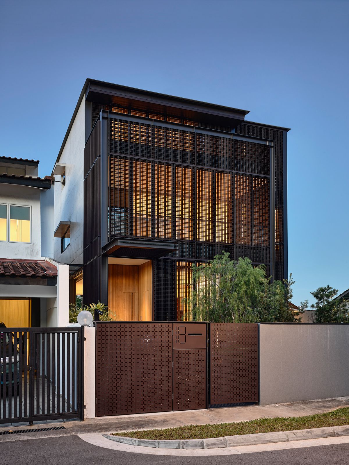 The interior of the detached house glows in the evening through the screen