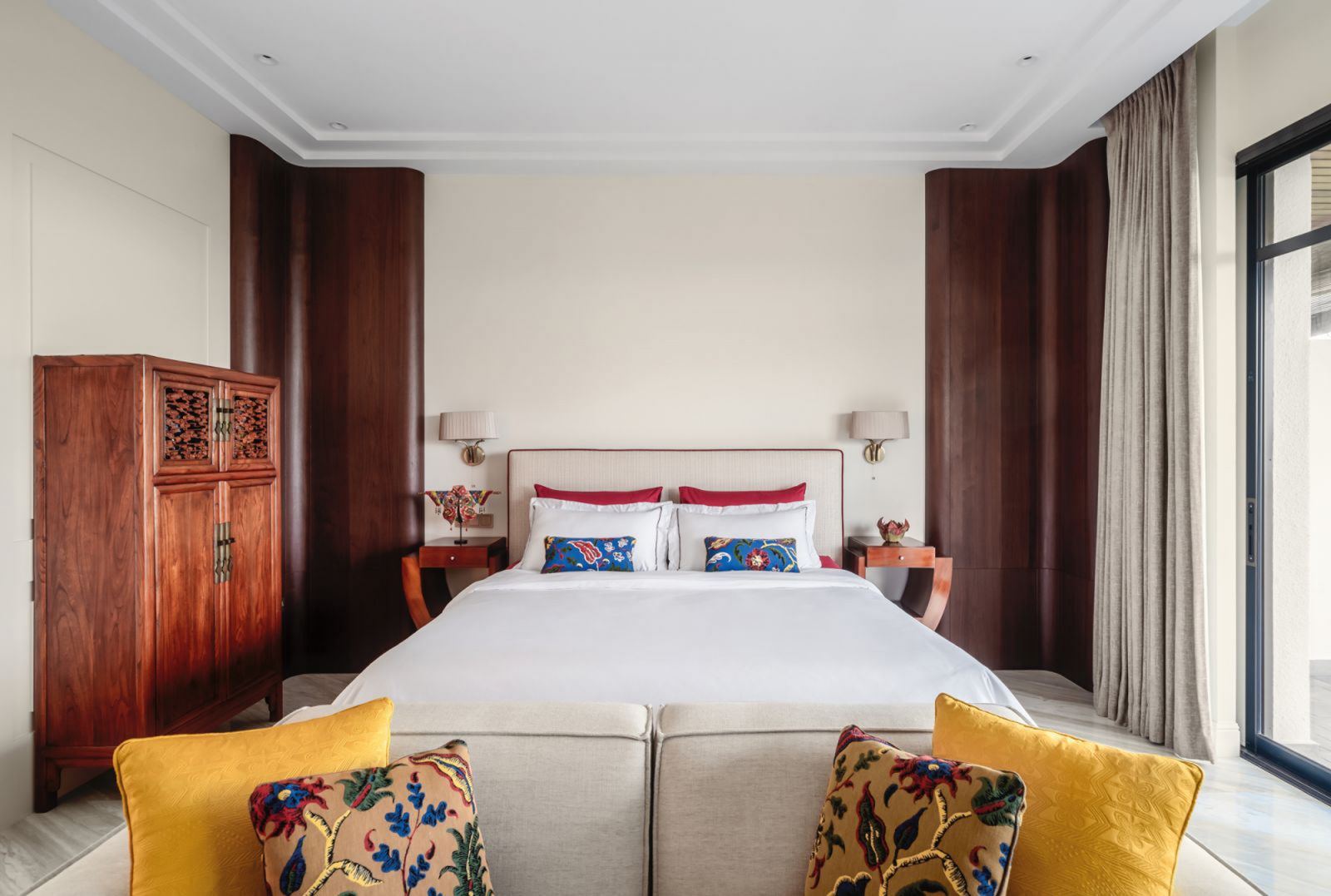 The master bedroom employs an understated neutral scheme, enlivened by a vibrant mix of accent cushions