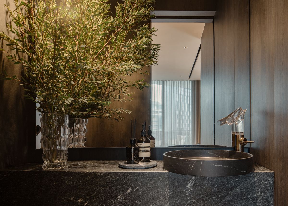 The Orchard Road apartment's powder room conceals an unsightly ventilation window with a stylish stainless steel curved mirror