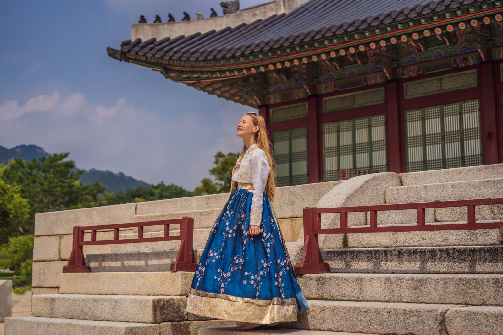 Young caucasian female tourist in hanbok national korean dress at Gyeongbokgung Palace. Travel to Korea concept. National Korean clothing. Entertainment for tourists - trying on national Korean clothing.