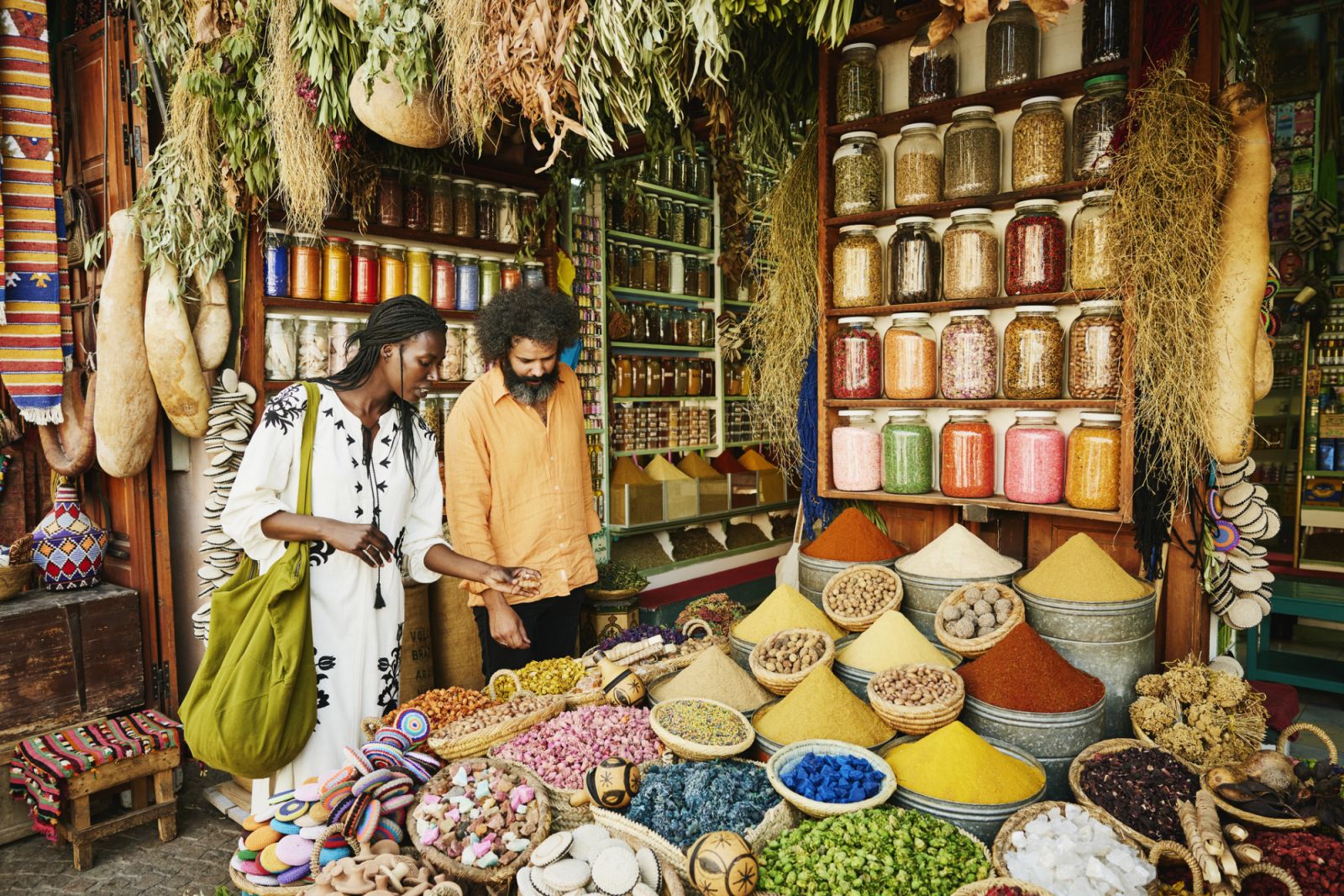 Wide shot of couple shopping in spice shop in the souks of Marrakech while on vacation