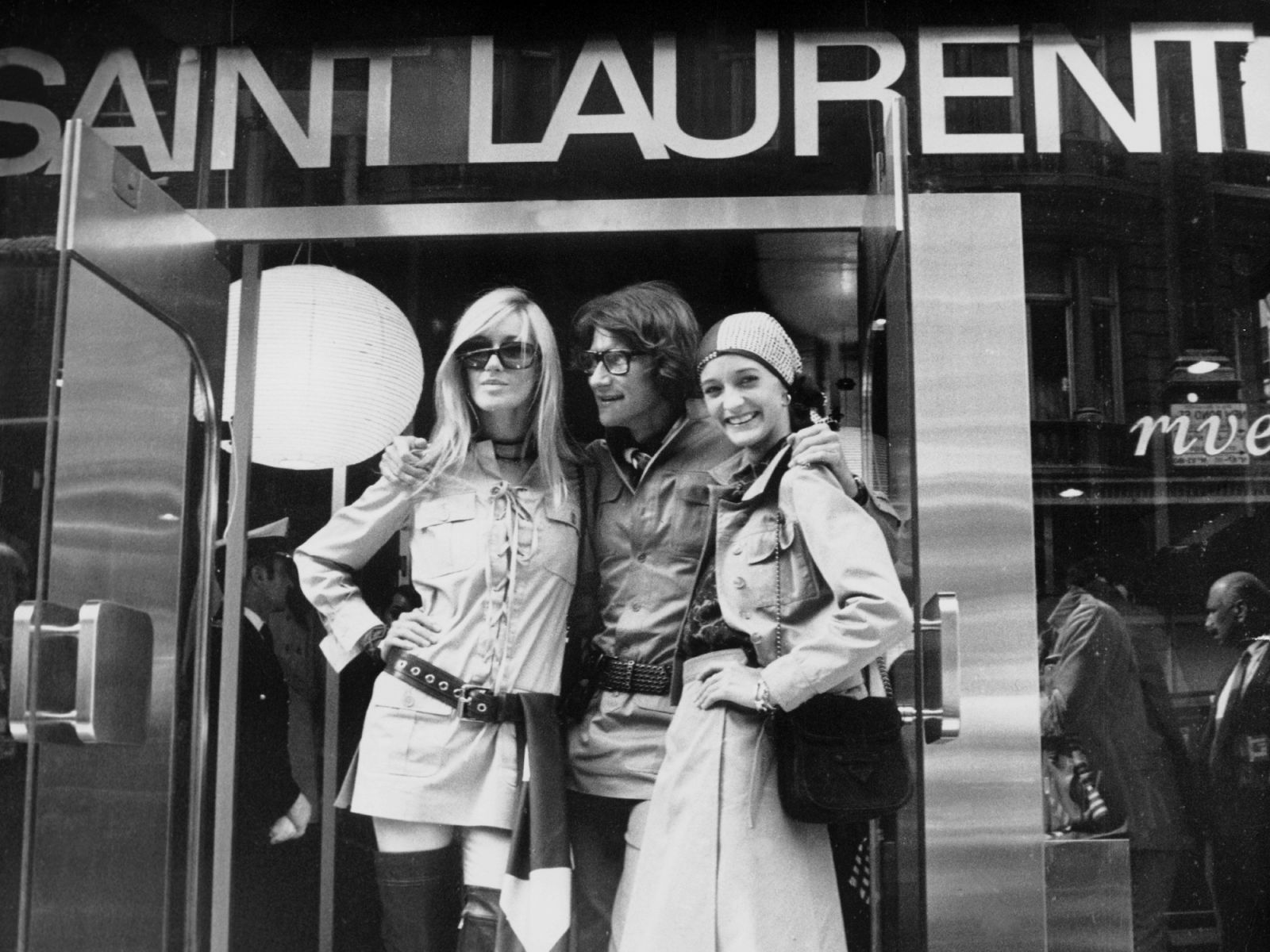 LONDON, UNITED KINGDOM - SEPTEMBER 10: French fashion designer Yves Saint Laurent posing in front of his new shop in Bond Street on September 10, 1969 in London, United Kingdom. He is with two model friends Betty Catroux (left) and Loulou De La Falaise - It was the first ready-to-wear shop that the fashion designer had opened in London and he called it Yves Saint Laurent Rive Gauche, as his first shop in Paris. (Photo by Keystone-France/Gamma-Keystone via Getty Images)