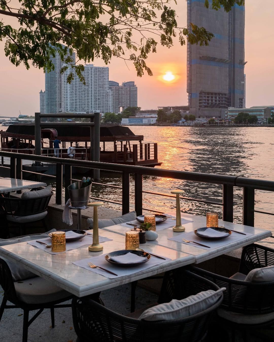 บรรยากาศยามพระอาทิตย์ตกริมน้ำเจ้าพระ บริเวณโซนที่นั่งเอาท์ดอร์ของร้าน Phra Nakhon ในโรงแรม Capella Bangkok (ภาพ: Instagram / @phranakhon.bangkok)