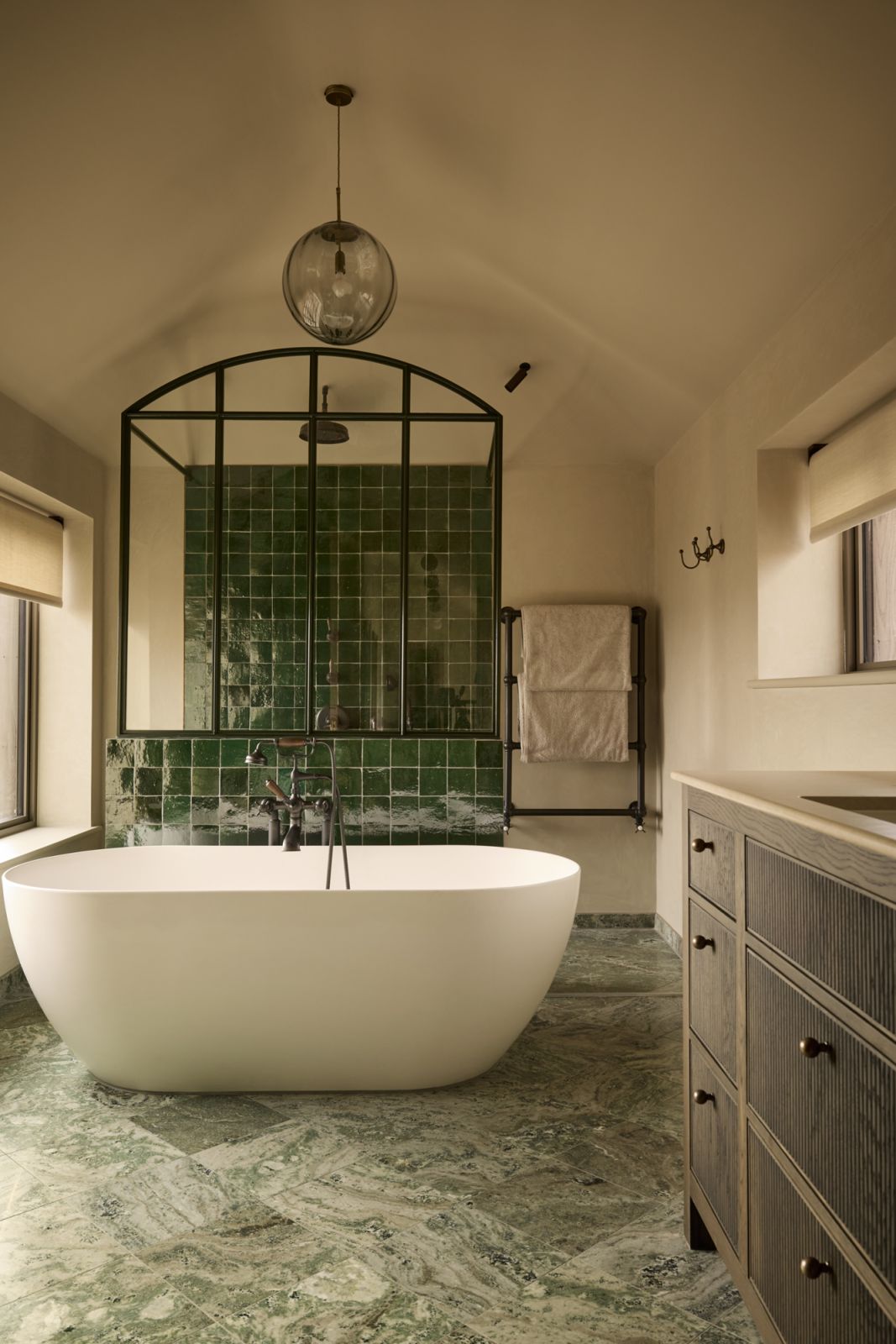 The green-hued family bathroom with a bespoke curved bath screen