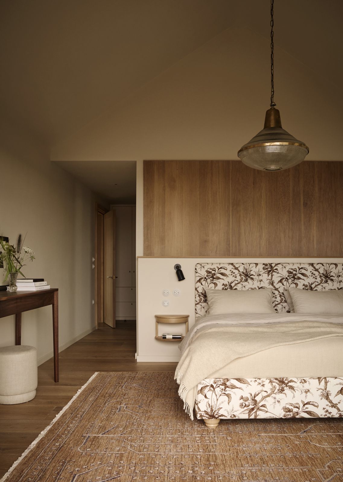 The wood-toned main bedroom with a custom-designed fabric headboard in Pomona Tobacco