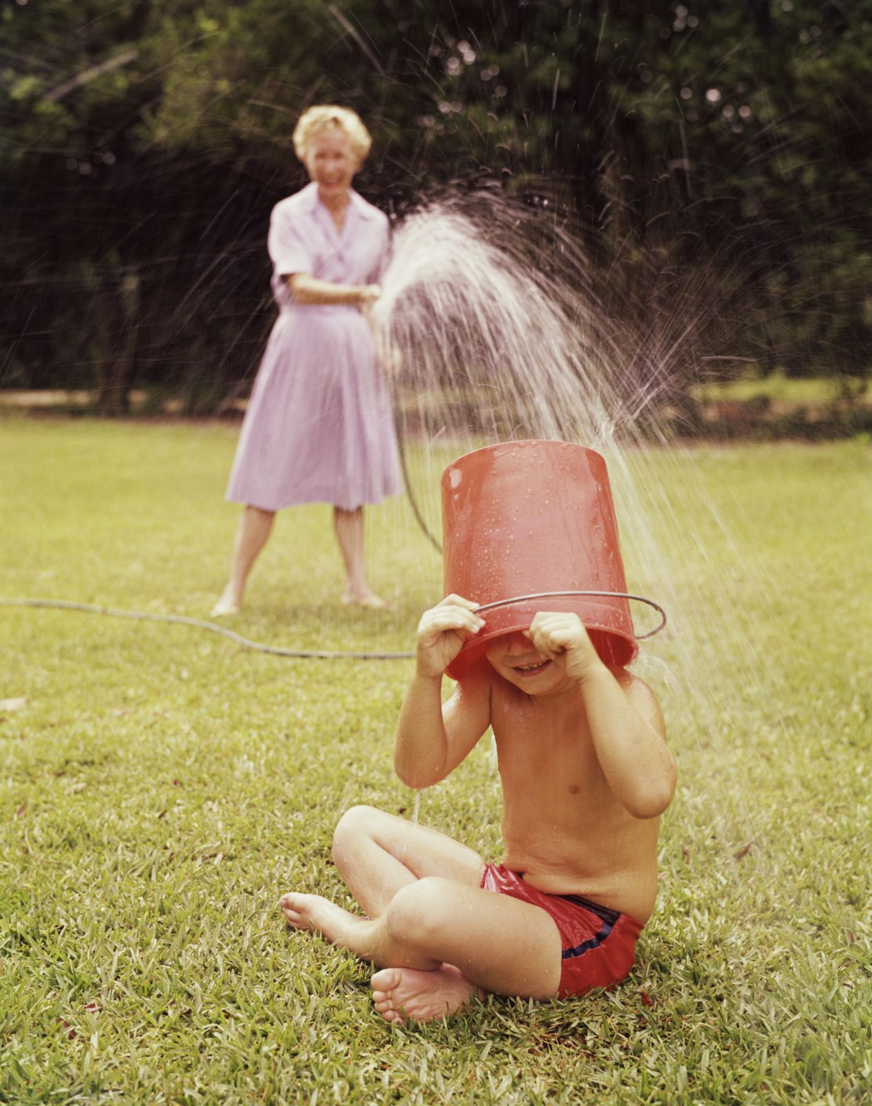 Mother spraying son with hose