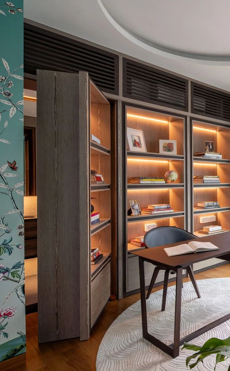 The door to the bathroom is seamlessly integrated into the bookcase wall in the wife’s study