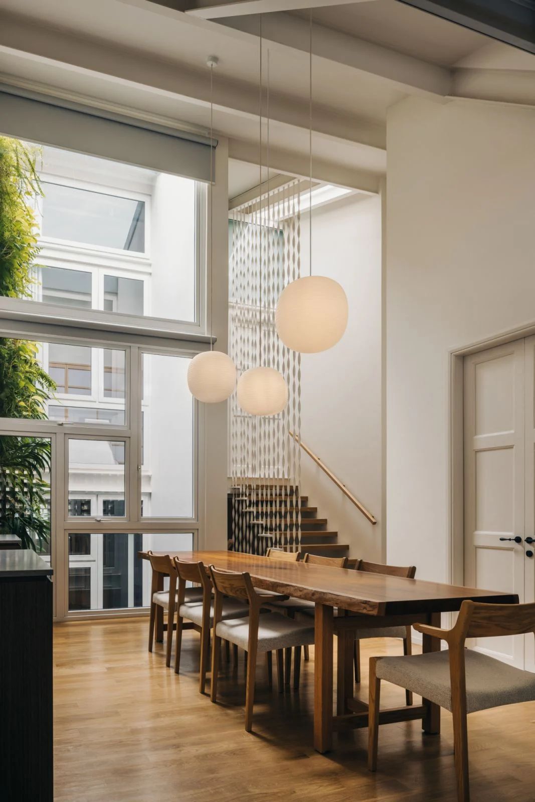 The dining room benefits from natural illumination and greenery thanks to the landscaped light well