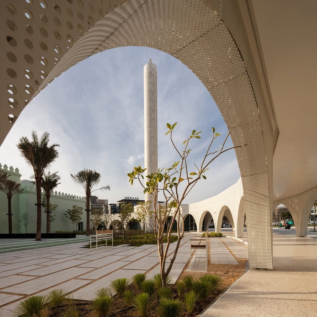 The minaret that doubles as a wind turbine enclosure framed by the white perforated metal colonnade (Photo: Instagram / @waiwaidesign)
