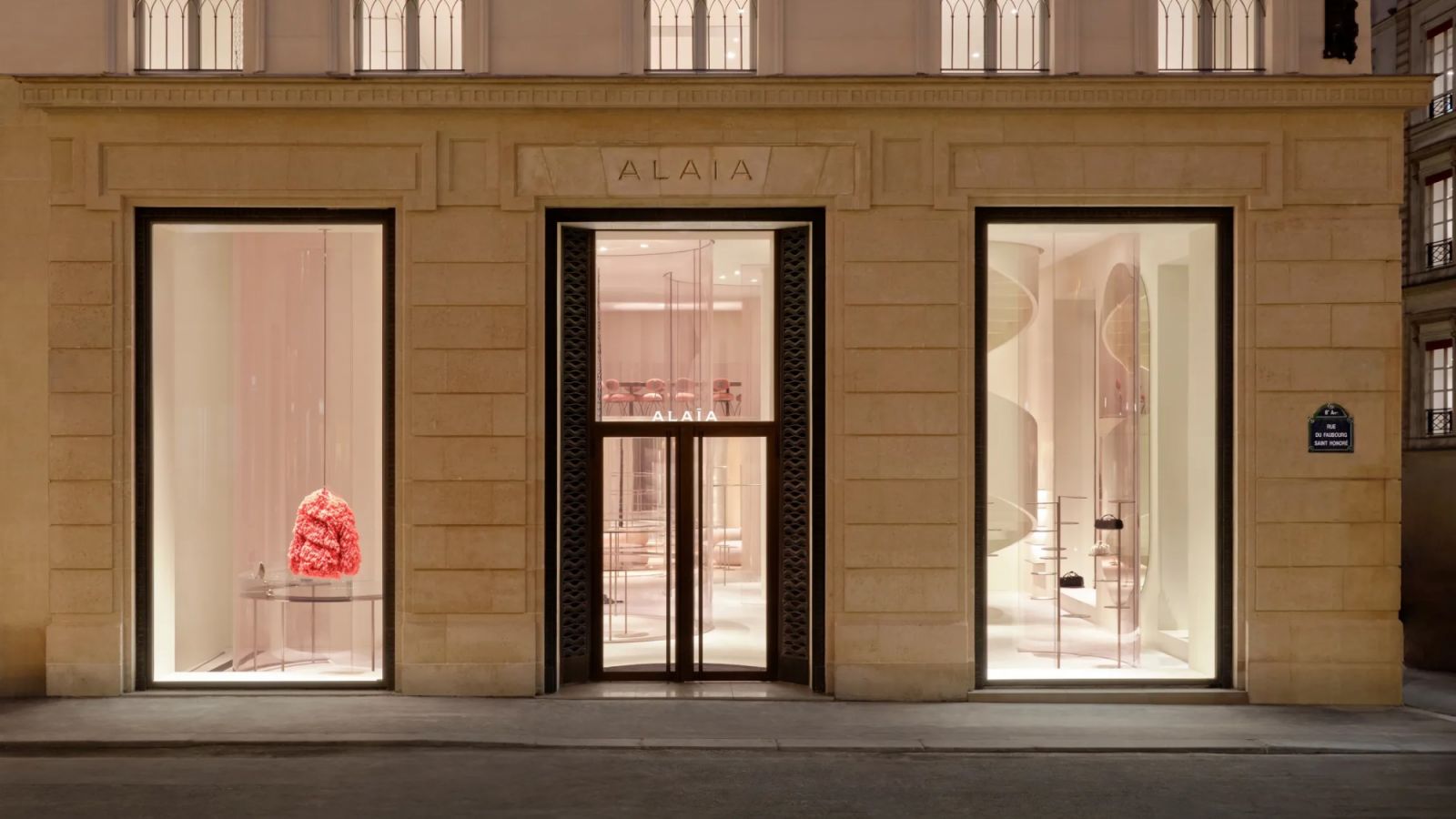 The limestone façade of the Alaïa flagship in Paris, featuring elegant arched windows and minimalist display cases (Photo: Alaïa)