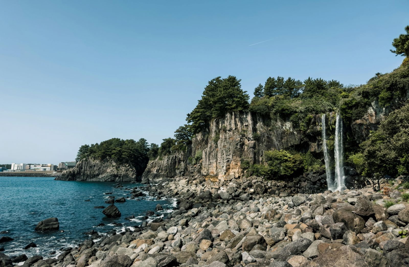 Take in the natural charms of Jeju Island. (Photo: Photo by Kharl Anthony Paica: https://www.pexels.com/photo/a-rocky-shoreline-with-a-waterfall-and-a-rocky-cliff-16663092/