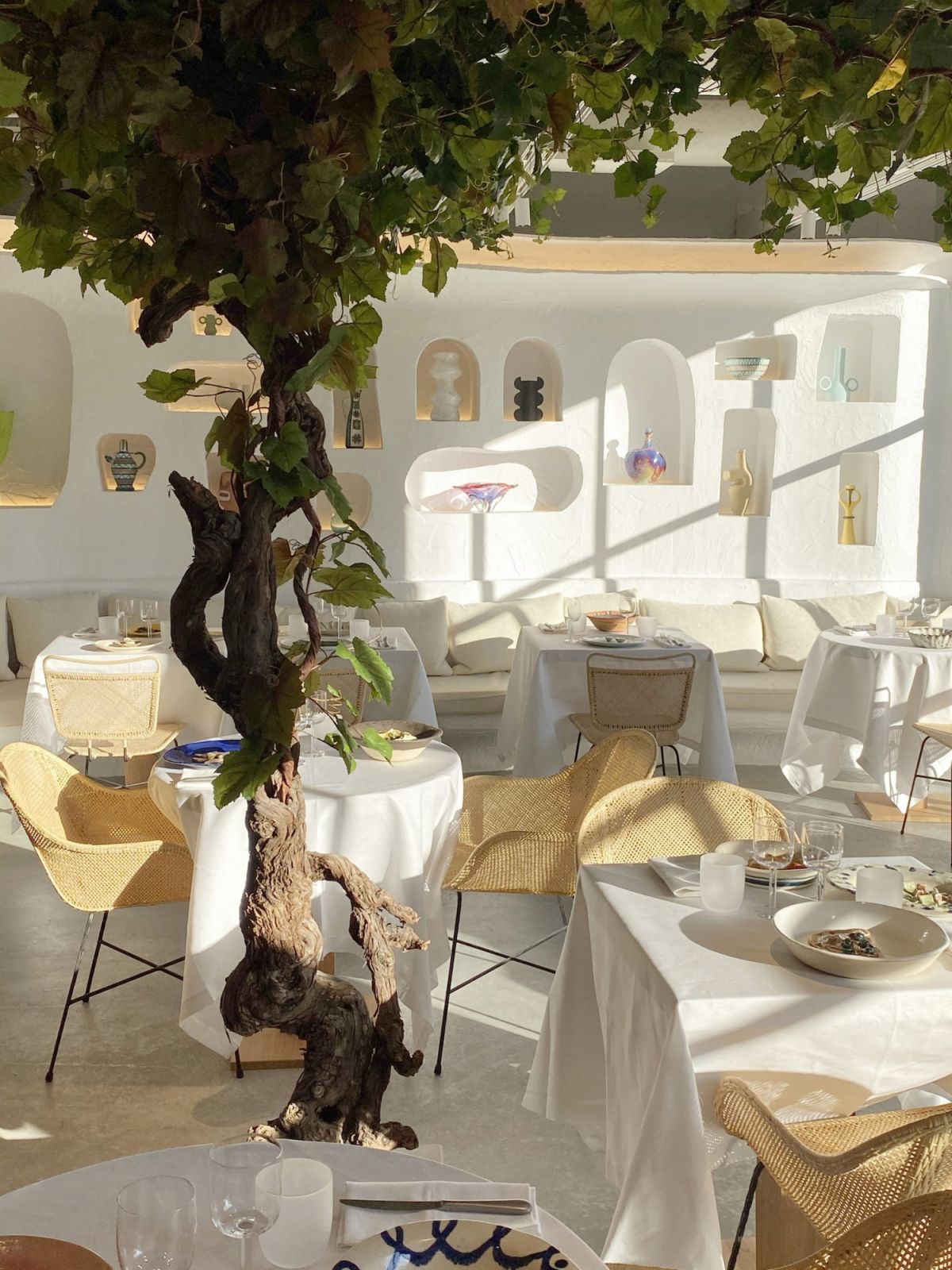 Sunlight streams through the Café Oursin dining space, highlighting the textured white walls and carefully curated ceramic pieces (Photo: Jacquemus)